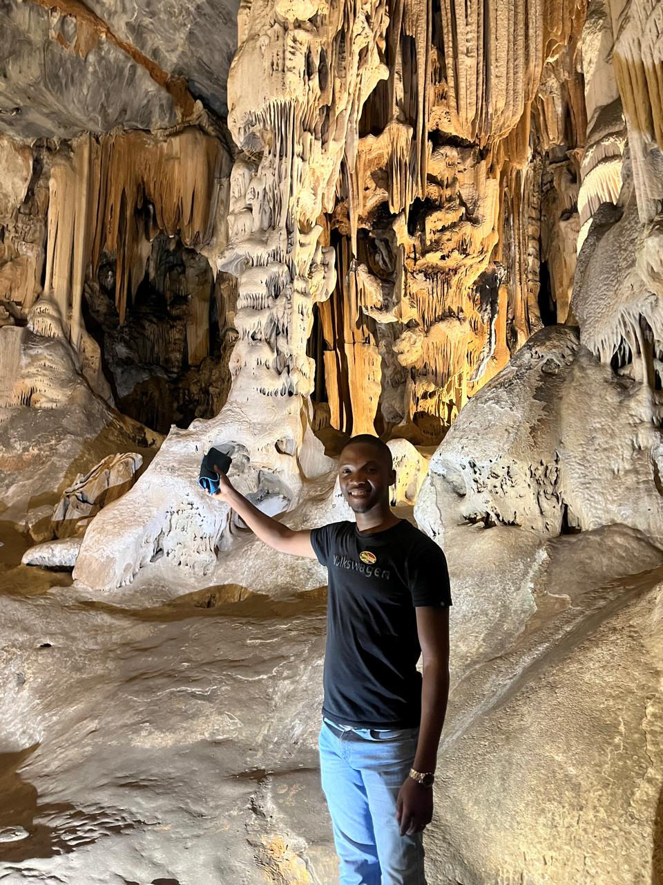 Guide exploring illuminated limestone formations at Cango Caves