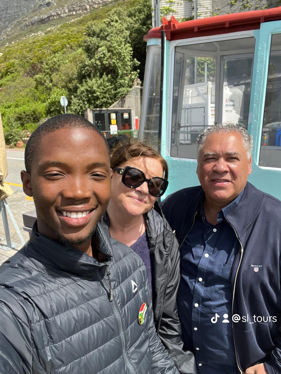 Guide and guests smiling beside Table Mountain cableway station, Cape Town