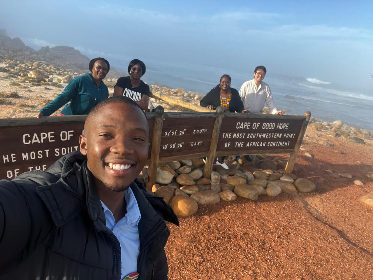 Guide and guests at the Cape of Good Hope sign, Cape Peninsula
